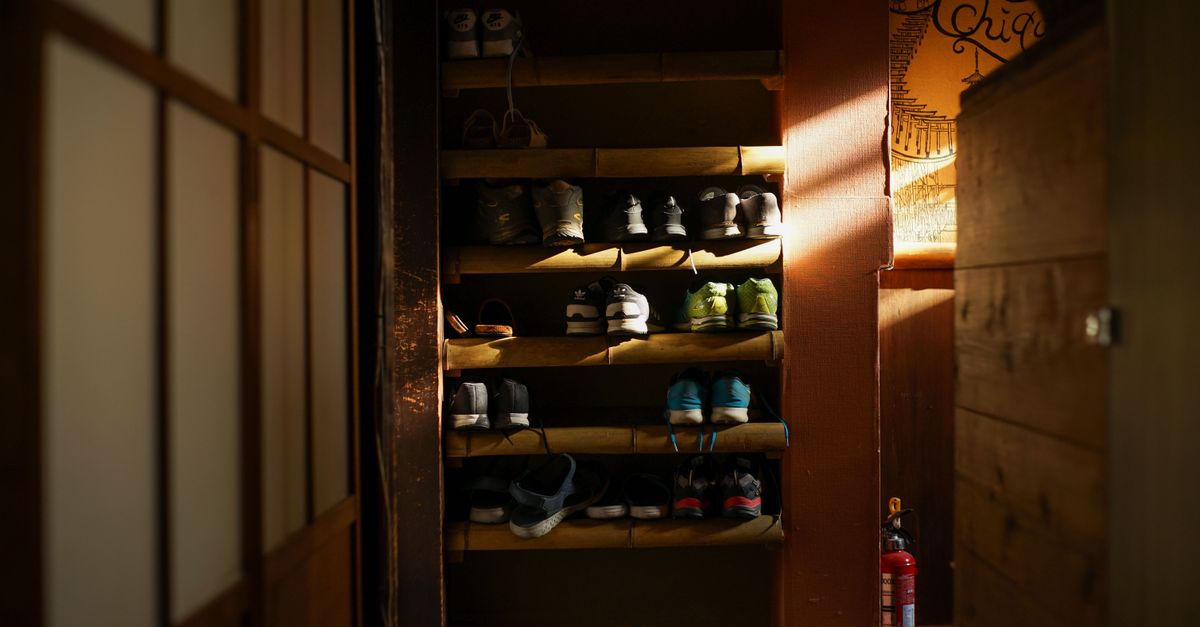 Warmly lit shoe rack featuring organized sneakers in a traditional Kyoto residence.